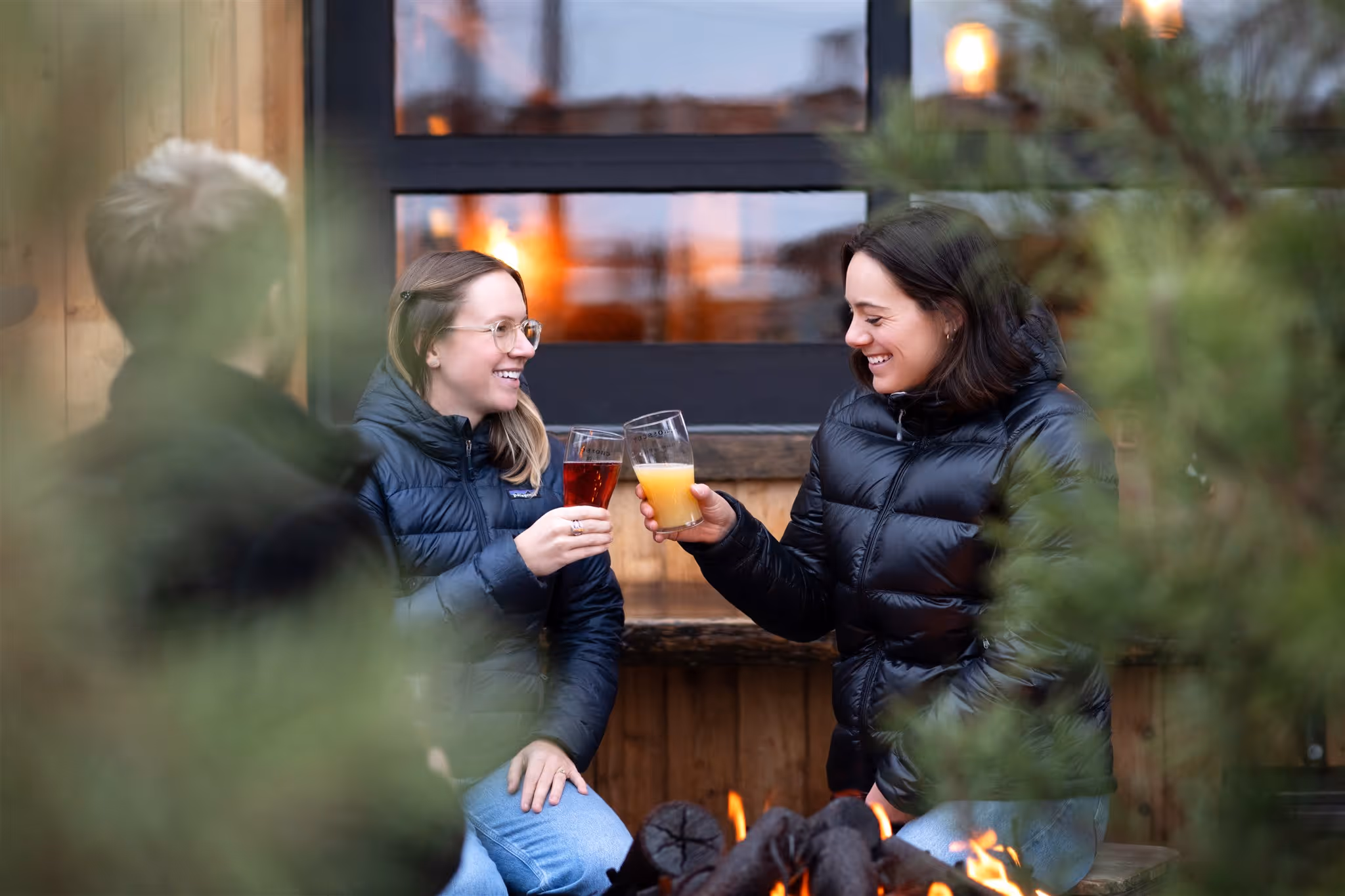 Two teammates toasting drinks beside a fire